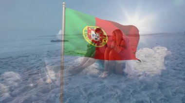 Sahilde oturmuş, animasyon arka planında sallanan Portekiz bayrağını izleyen bir çift. Seyahat, tatil, rahatlama, manzara, tatil