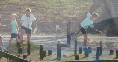 Okulda, çocuklar açık hava engelli parkurunda tahta direklerin üzerinden atlıyorlar. Oyuncu, macera, egzersiz, aktivite, animasyon, takım çalışması