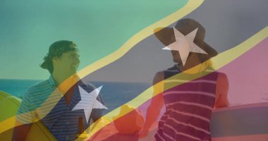 Saint Kitts ve Nevis bayrağı üzerinde sörf tahtası olan iki adam sahilde konuşuyor. Sörf, okyanus, sohbet, seyahat, tatil, ada