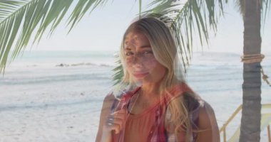 Palmiye ağacının altında, arka planda okyanus dalgalarıyla gülümseyen bir kadın, animasyonun tadını çıkarıyor. Tatil, tropikal, plaj, rahatlama, seyahat, doğa