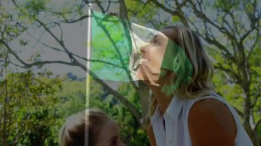 Çocuk, bayrak animasyonu ve ağaç arka planıyla yetişkinler tarafından kaldırılıyor. Kutlama, vatanseverlik, birliktelik, aile, destek, neşe