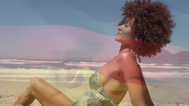 Sahilde dinlenen, renkli animasyonlu ve arkasında okyanus dalgaları olan bir kadın. Tatil, rahatlama, sahil hayatı, tropikal, dingin, yaz