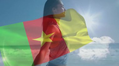 Kamerun bayrağıyla örtülmüş, kumsalda güneşlenen bir kadın. Tatil, tropikal, boş zaman, rahatlama, yaz, turizm