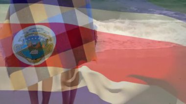 Renkli battaniyeye sarılmış, insanlar bayrak ve amblem animasyonlarıyla okyanus kenarında. Sahil, sahil, grup, seyahat, turizm, kıyı şeridi