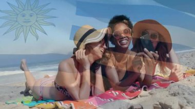 Sahilde dinlenen, Uruguay bayrağı animasyonlu güneş şapkalı üç kadın. Tatil, plaj kıyafeti, seyahat, boş zaman, güneş banyosu, tropik