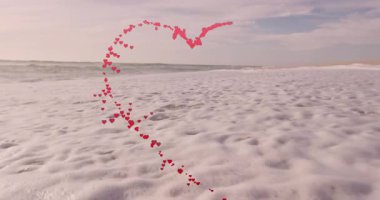 Sahildeki okyanus dalgaları üzerinde kırmızı ve pembe kalplerin kalp şeklinde animasyonu. Romantik, aşk, sevgililer günü, sahil, iç açıcı