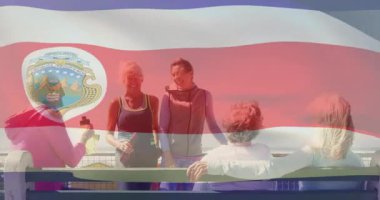 Bayrak sallıyor, bir grup insan açık havada amblemle görülüyor. Vatanseverlik, kutlama, birlik, çeşitlilik, toplanma, ulusal