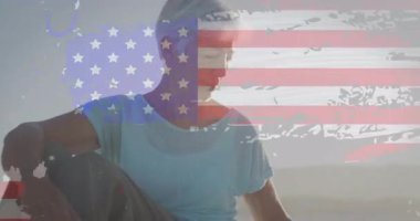 Açık havada oturan, Amerikan bayrağı animasyonu ile örtüşen ve soyut dokuları olan bir kadın. Vatanseverlik, özgürlük, kutlama, yaşam tarzı, konsept, ulusal