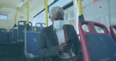 Otobüste akıllı telefon kullanan maskeli ve kulaklıklı adam animasyon verilerini izliyor. Teknoloji, seyahat, ulaşım, bağlantı, dijital, eğlence