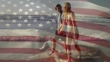 Sahilde yürüyen, arka planda Amerikan bayrağı animasyonu olan bir çift. Vatanseverlik, romantizm, kutlama, seyahat, tatil, tatil