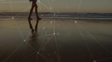 Sahilde yürüyen insan silueti ağ bağlantıları animasyon örtüsüyle. Teknoloji, bağlantı, yenilik, dijital, fütüristik, iletişim