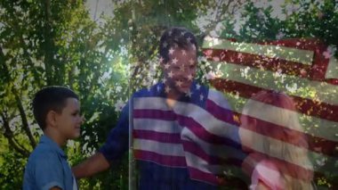 Açık havada, çocuklu baba, Amerikan bayrağı animasyonu vatanseverlik sahnesi yaratıyor. Aile, vatanseverlik, birliktelik, birlik, bağımsızlık, kutlama