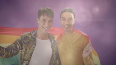 Gökkuşağı bayrağına sarılmış, yumuşak mor arka plan animasyonuna gülümseyen iki kişi. LGBTQ, gurur, çeşitlilik, aşk, eşitlik, kutlama