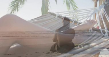 Hamakta dinlenen, plaj sahnesinde palmiye ağaçları ve okyanus animasyonlarıyla eğlenen biri. Tropik, cennet, rahatlama, tatil, dinlenme, huzur