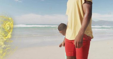 Sahilde yürürken, sarı tişörtlü adam ışıltı animasyonuyla çevrili. Yaz, tatil, deniz kenarı, boş zaman, dinlenme, ışıl ışıl