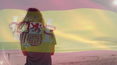 Sahilde, İspanyol bayrağı animasyonu sahnesiyle rahatlayan insanlar. Tatil, turizm, güneş ışığı, okyanus, sahil şeridi, dinlenme