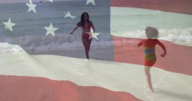 Sahilde, kadın ve çocuk Amerikan bayrağı animasyonlarıyla oynuyorlar. Vatanseverlik, yaz, aile, tatil, deniz kenarı, özgürlük