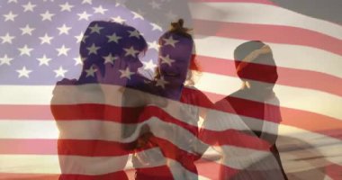 Amerikan bayrağı kaplaması, kumsalda gün batımını izleyen kadınlar, animasyon etkisi yaratıyor. Vatanseverlik, animasyon, siluet, huzur, özgürlük, deniz kenarı