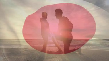 Sahilde, Japon bayrağıyla örtülü siluetli bir çift günbatımı animasyonunu izliyordu. Romantizm, vatanseverlik, sükunet, tatil, huzur