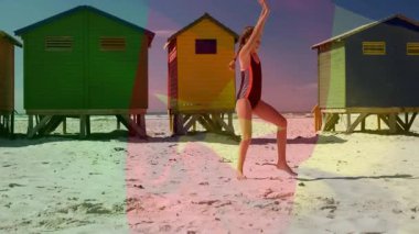 Sahilde, çocuk renkli kulübelerle ve animasyon bayrağıyla takla atıyor. Tatil, deniz kenarı, çocukluk, jimnastik, yaz, oyuncu