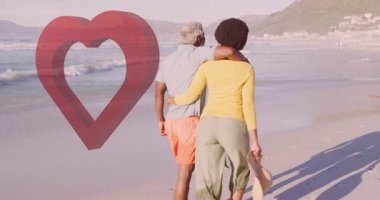 Okyanus arka planında kalp şeklinde animasyonları olan plajda yürüyen çift. Aşk, aşk, tatil, sevgililer günü, deniz kenarı, gün batımı