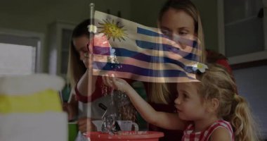 Uruguay, anne ve kızının mutfakta birlikte yemek pişirmesi üzerine bayrak animasyonu. Aile, yemek pişirme, kaynaşma, annelik, aile içi, aşçılık