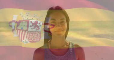 Gün batımında sahilde dikilen İspanyol bayrağıyla gülümseyen kadın. Tatil, seyahat, vatanseverlik, eğlence, turizm, kıyı