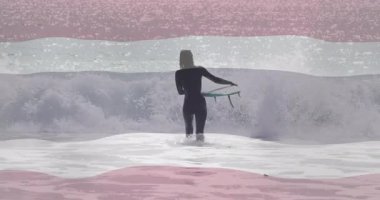 Okyanus dalgalarına soyut pembe ve beyaz kaplamalı animasyonlarla giren sörfçü. Sörf, sahil, sahil, yaz