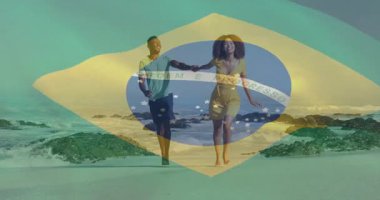 Sahilde yürüyen, elinde Brezilya bayrağı olan bir çift. tatil, seyahat, kutlama, neşe