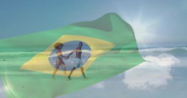 Sahilde el ele tutuşan, parlak güneşin altında Brezilya bayrağı taşıyan bir çift. Romantizm, tatil, yaz, eğlence, vatanseverlik, milliyet