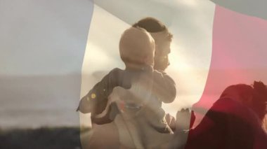 Aile, arka planda bayrak hareketleriyle dışarıda vakit geçiriyor. Vatanseverlik, kutlama, eğlence, kaynaşma, piknik, kardeşler