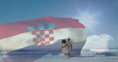 Güneşli sahilde Hırvat bayrağı sallarken, yanında iki kişi vardı. Vatanseverlik, yaz, tatil, sahil, kutlama, deniz kıyısı