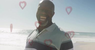 Sahilde gülümseyen bir adamın etrafında yüzen kalp şekillerinin animasyonu. Valentine, romantizm, mutluluk, tatil, mutluluk, deniz kenarı