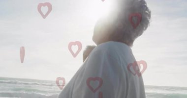 Sahilde yürüyen, kalp şeklinde animasyonları olan son sınıf öğrencisi. Okyanus, rahatlama, tatil, sağlık, rahatlama, tatil