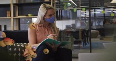 Modern ofiste yüzen emoji animasyonlarını tartışan maskeler takan insanlar. İş, takım çalışması, işbirliği, teknoloji, iletişim, toplantı