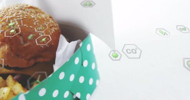 Hamburger ve patates kızartması kutuda, çevre dostu ikonlar animasyonu örtüyor. Fast food, abur cubur, yemek, paket servis, ambalaj, sürdürülebilirlik