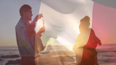 Sahilde, aile günbatımını izlerken arka planda bayrak sallıyor, rahatlamış hissediyordu. Tatil, sahil şeridi, boş zaman, aile zamanı, sükunet, akşam