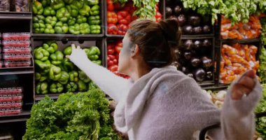 Yeşil dolma biber seçmek, markette dijital arayüz kullanan bir kadın. Alışveriş, teknoloji, süpermarket, üretim, sebze, tüketici