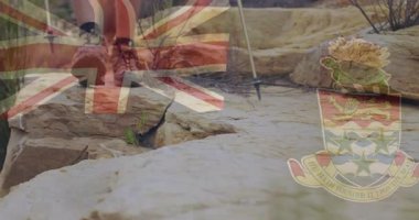 Kayalık arazide İngiliz bayrağı ve Cayman Adaları armasıyla yürüyüş yapmak. Macera, keşif, açık hava, seyahat, yürüyüş, doğa.