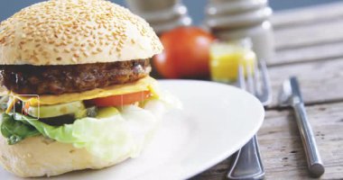 Hamburger, beslenme verileri ve canlandırma ikonları ile mutfakta tabağı kaplıyor. Fast food, sağlıklı beslenme, gurme, konfor, mutfak, dijital