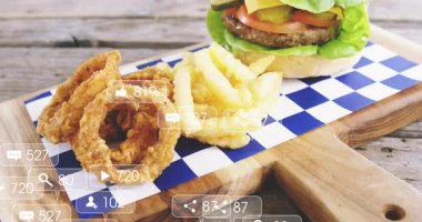 Tahta tahtada hamburger ve patates kızartması ve sosyal medya bildirimleri. Fast food, digital, communication, technology, concept