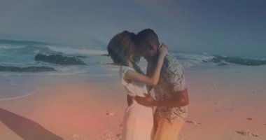 Kumsalda kucaklaşan, okyanus dalgalı bir çift, animasyon arka planı yaratıyor. Aşk, gün batımı, tatil, deniz kenarı