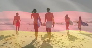 Sahilde yürüyen sörfçüler, Alman bayrağı taşıyan sörfçüler. Sörf, okyanus, spor, tatil, seyahat, macera