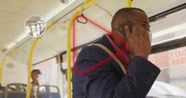 Otobüste dikilmiş, maskeli bir adam telefonda konuşuyor. Ulaşım, seyahat, şehir hayatı, toplu taşıma, teknoloji, iletişim