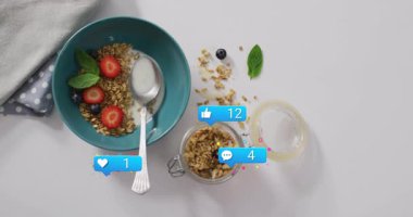 Mutfakta sosyal medya bildirimleri eşliğinde tahıl gevreği ve meyve yemek. Kahvaltı, sağlıklı beslenme, beslenme, dijital yaşam tarzı, çoklu görev, sağlık