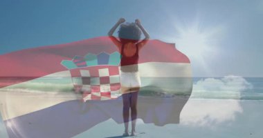 Sahilde, parlak güneş ışığı animasyonuyla Hırvat bayrağı üzerinde kollarını kaldıran kişi. Seyahat, tatil, kutlama, vatanseverlik, deniz kenarı, yaz