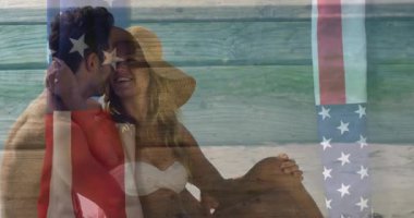 Kumsalda dinlenen çift, Amerikan bayrağıyla animasyonun tadını çıkarıyor. Tatil, seyahat, eğlence, romantizm, rahatlama, okyanus