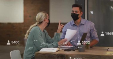 Sosyal medya simgelerinin örtüştüğü belgeler, maske takan iki meslektaş. İşbirliği, takım çalışması, ofis, salgın, koruma, yenilik