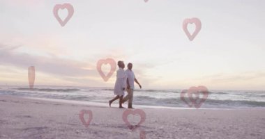Sahilde yürüyen, yaşlı bir çift kalp şeklinde animasyonlarla çevrili. Aşk, yaşlılar, aşk, tatil
