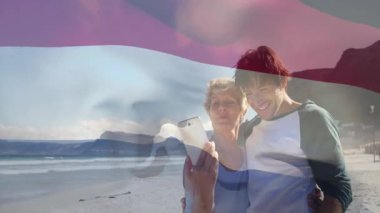 Sahilde selfie çeken, animasyonda bayrak sallayan bir çift. Seyahat, tatil, macera, okyanus, vatanseverlik, yaz